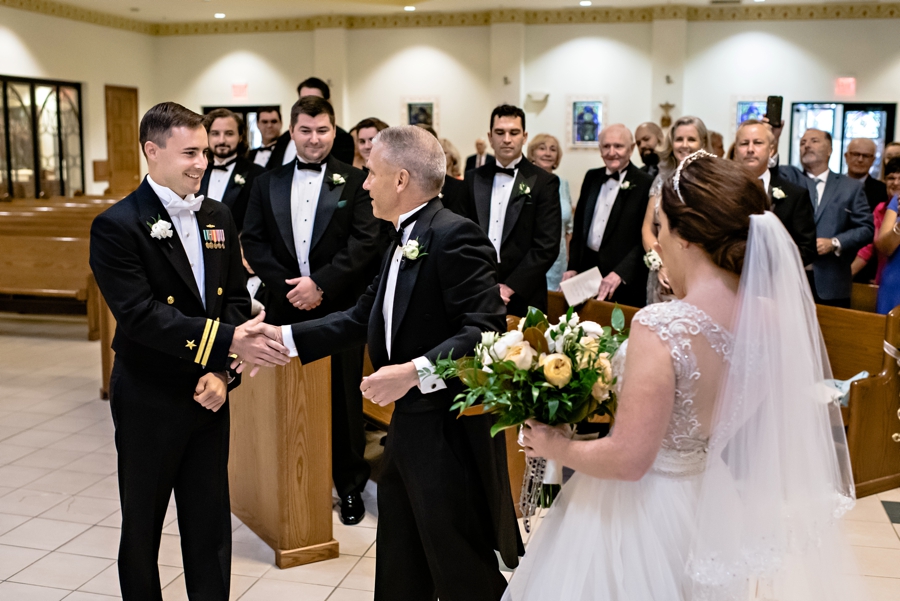 The father of the bride shakes hands with the groom at the end of the isle.